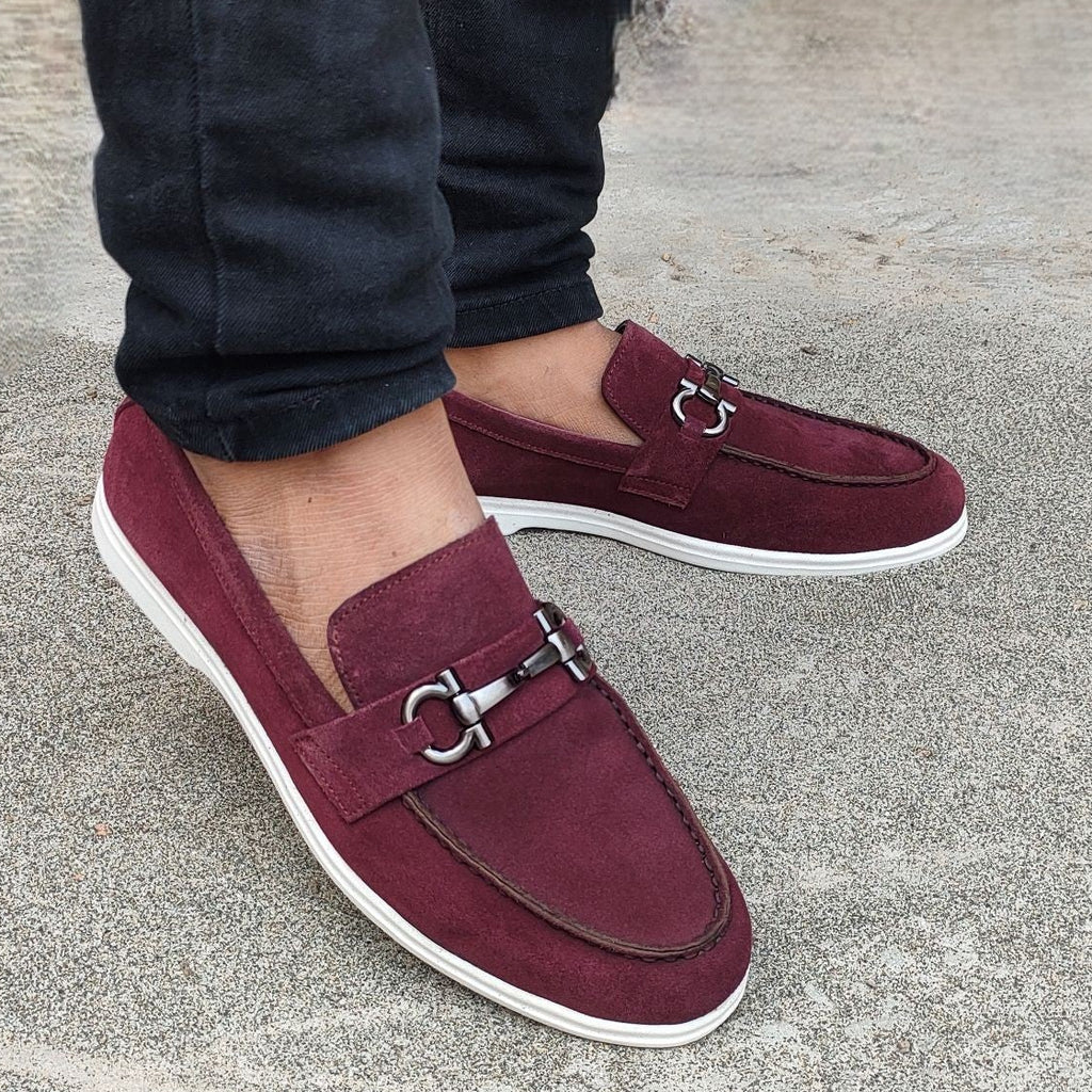 Burgundy loafers worn with pants on a concrete surface