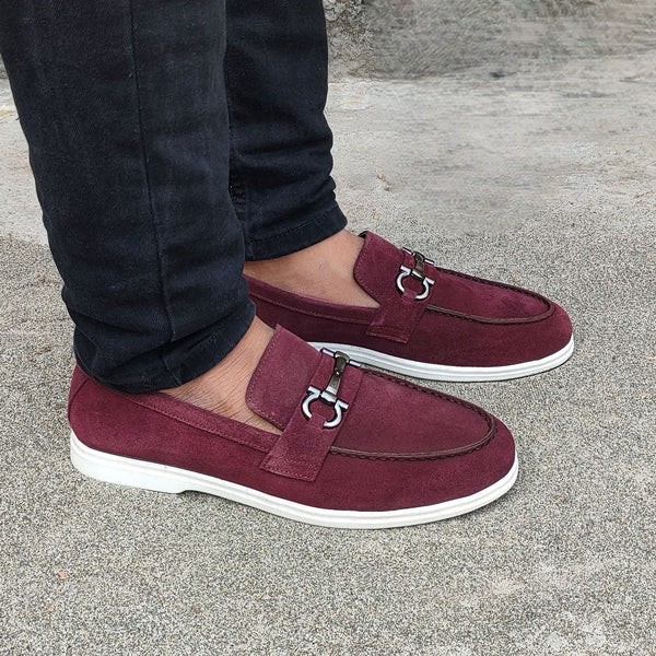 Person wearing maroon loafers with a stone wall background