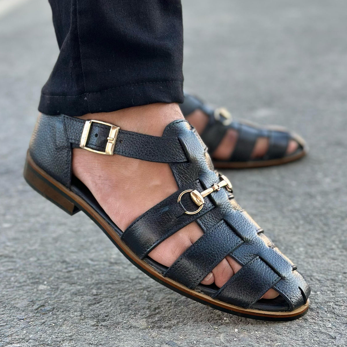 black leather sandals with metal buckles and a rubber sole.