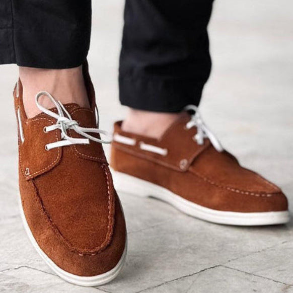 Brown suede shoes worn with black pants on a blurred background
