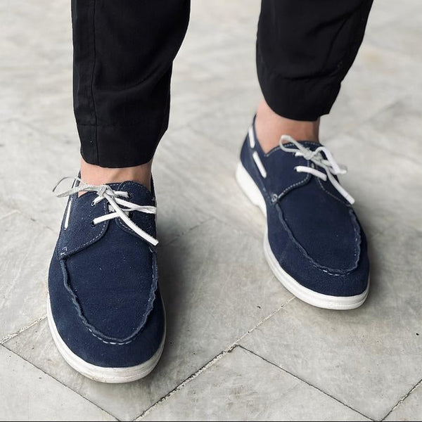 Navy blue shoes worn with black pants on a stone pavement